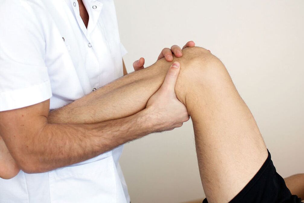 The doctor examines the knee with arthrosis